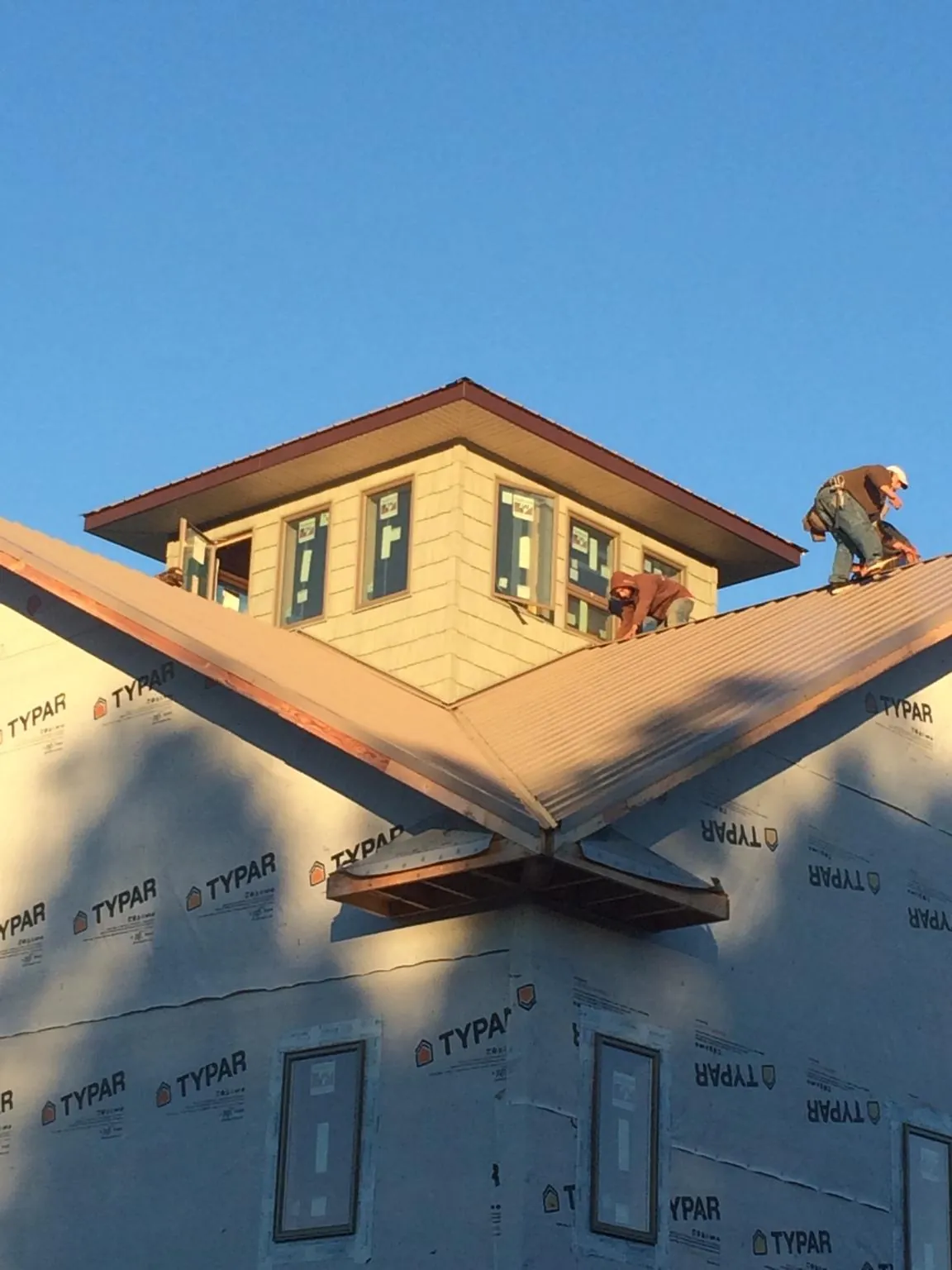 Roofers working around a rooftop cupola on a new metal roof at sunset — Roof Waterproofing in Russell by Roofing Brothers